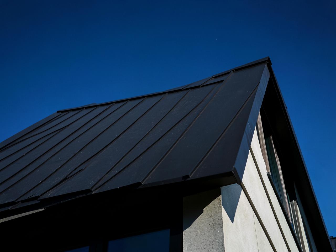 Dark standing seam metal roof against a deep blue sky